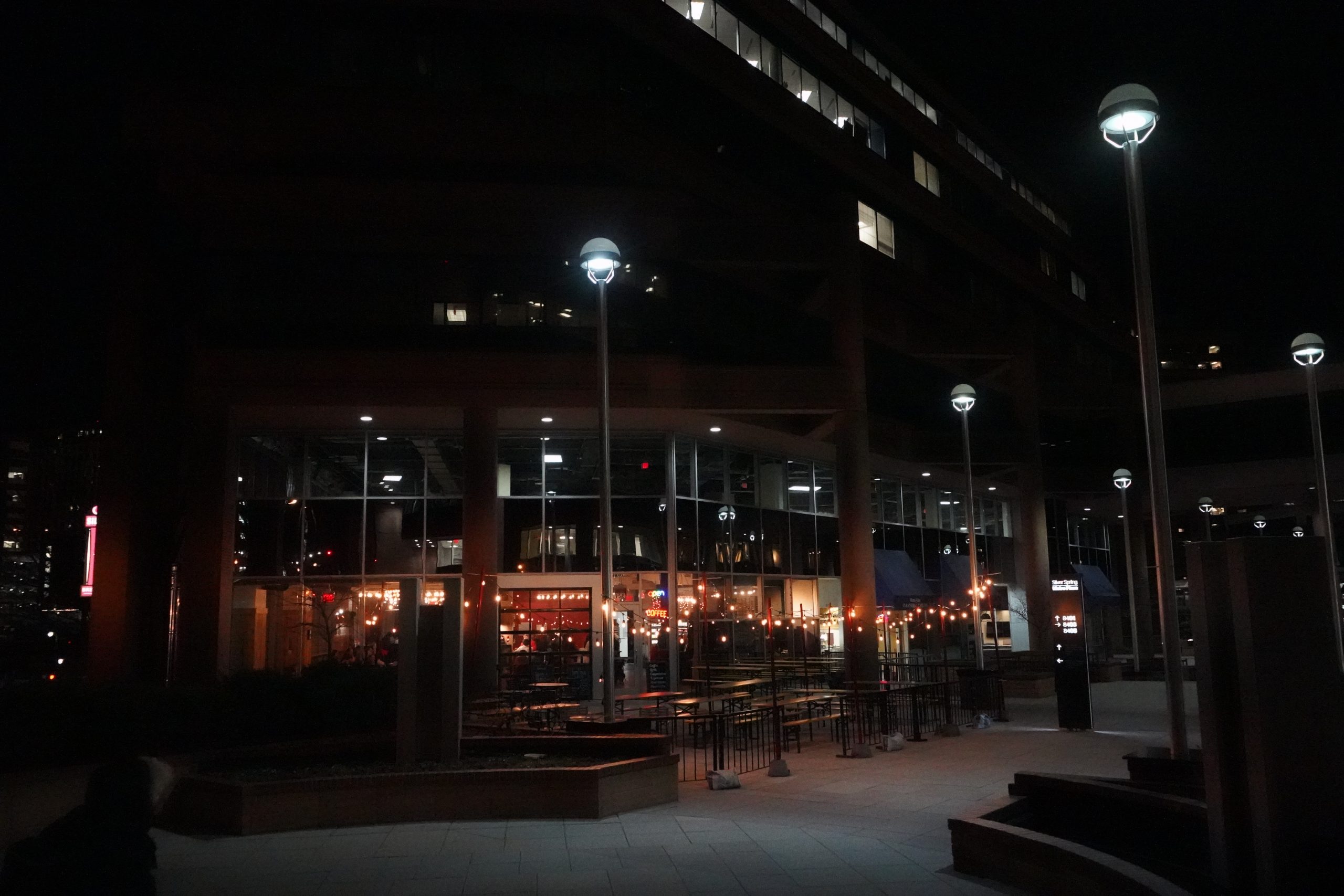 Outdoors view of the lit up pub in it's relatively quiet plaza locale.