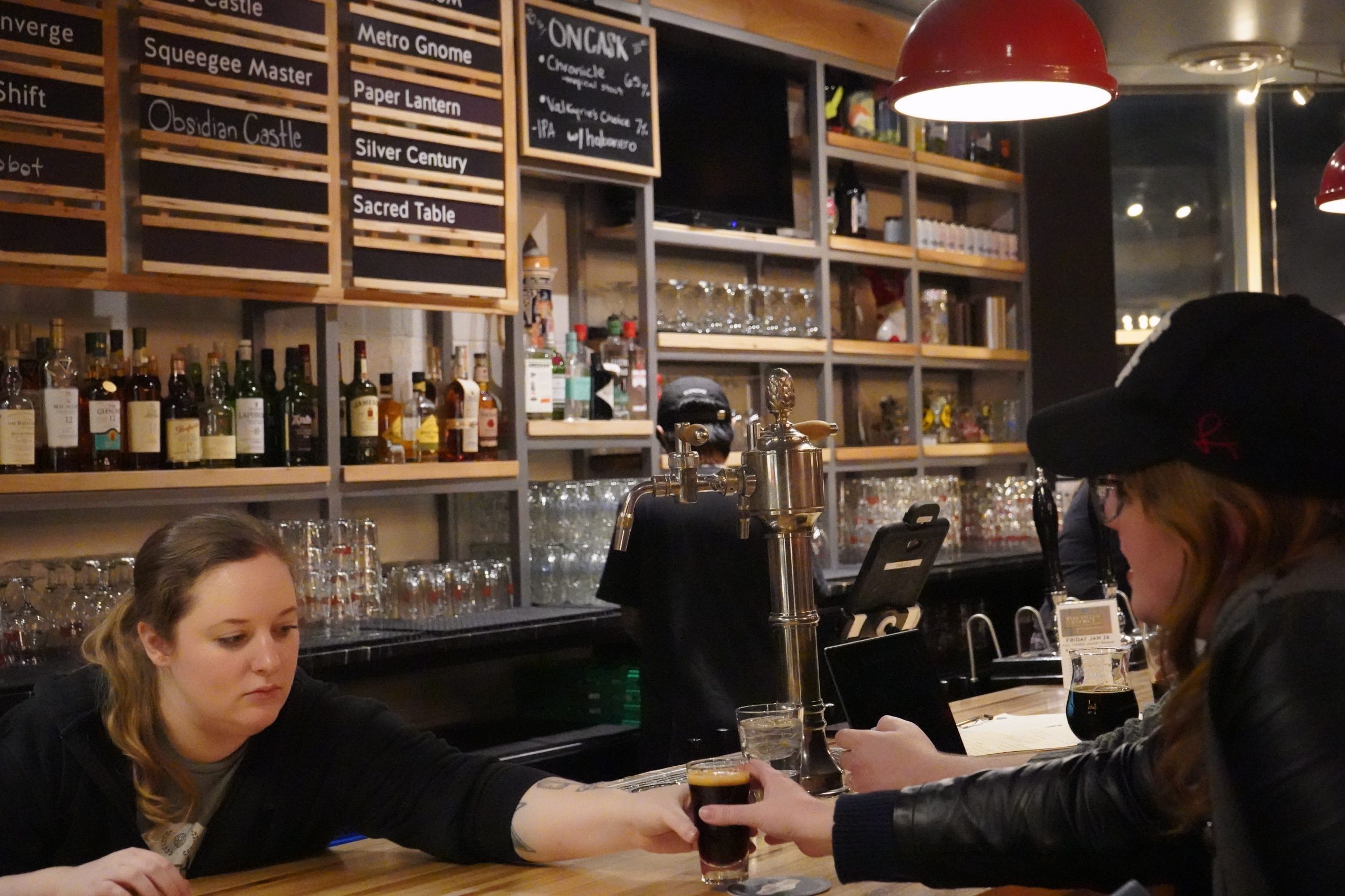 Mary, a manager at Silver Branch, hands a drink across the bar to a patron.