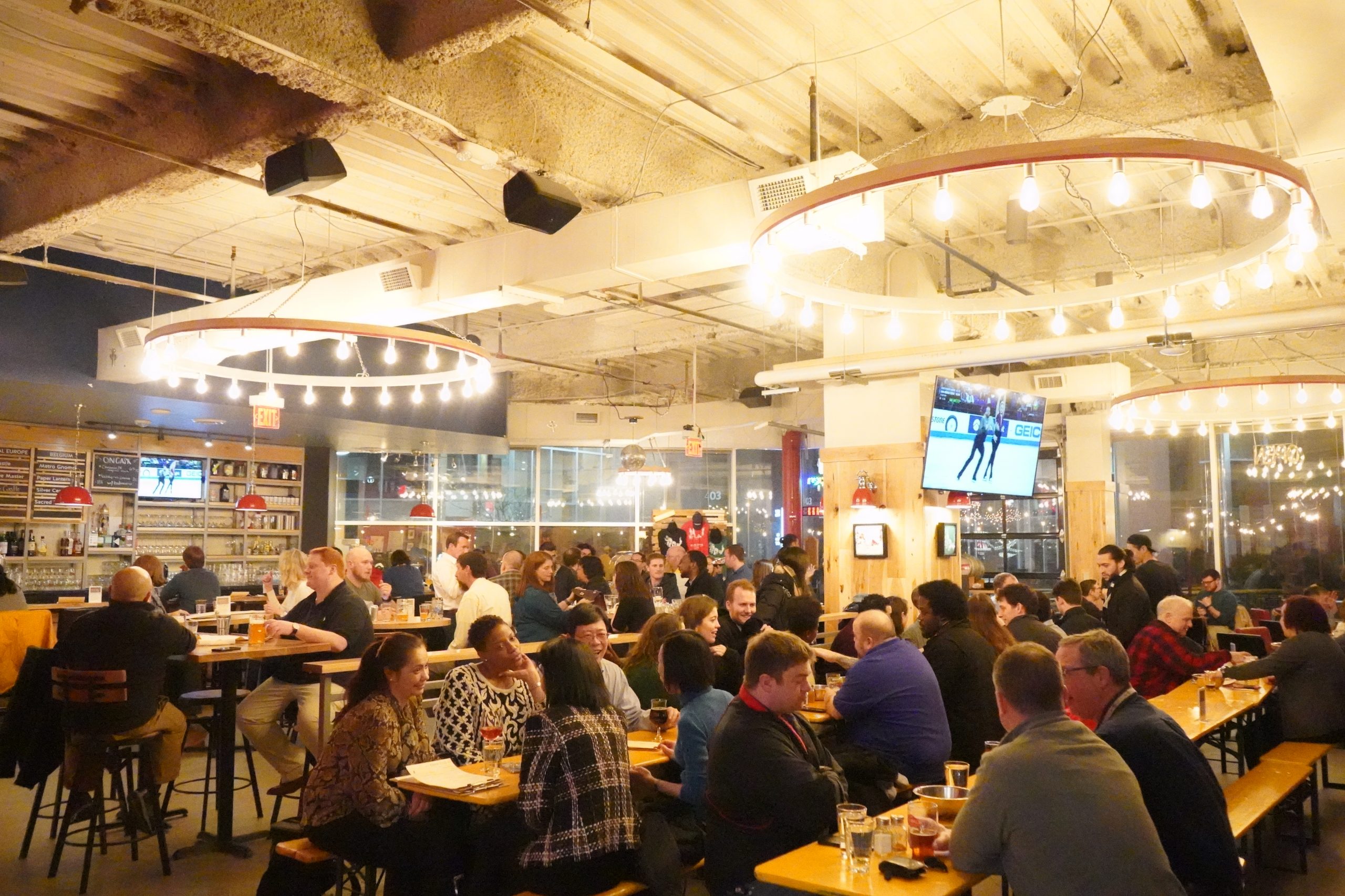 Wide view of a packed pub with an open converted warehouse like design.