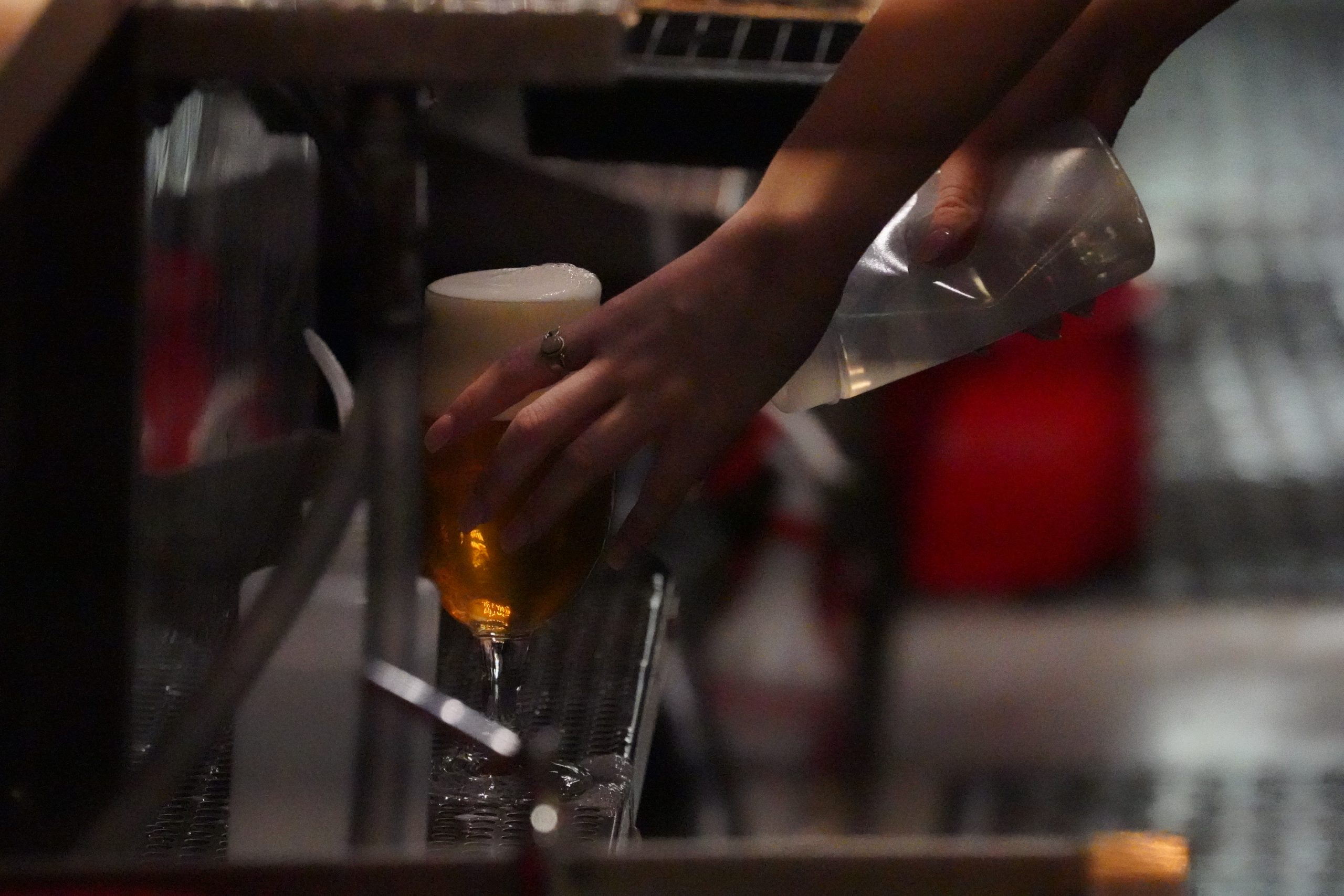 A bartender finishing off the perfect pour behind the bar.