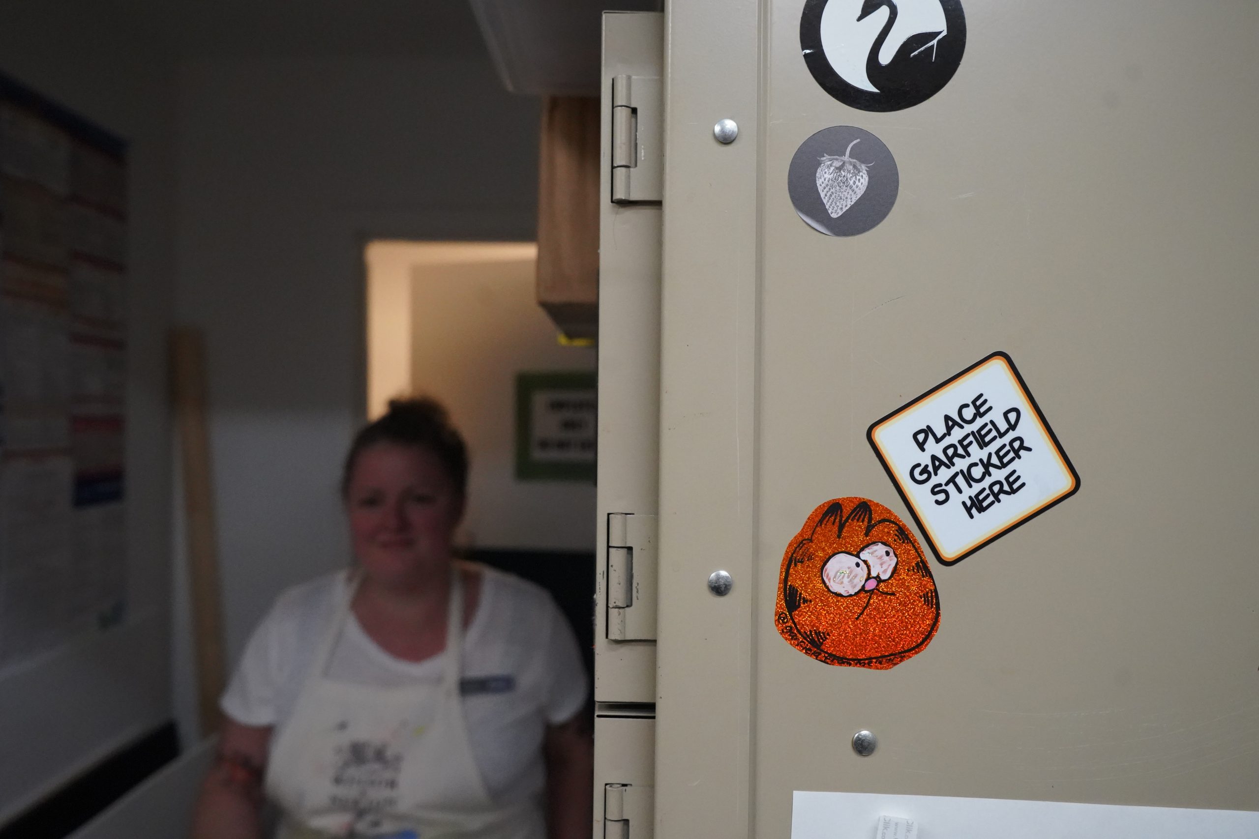 A Garfield from memory sticker on a locker with Kate Parnell out of focus walking in the background at Plaza Art in Washington, DC.