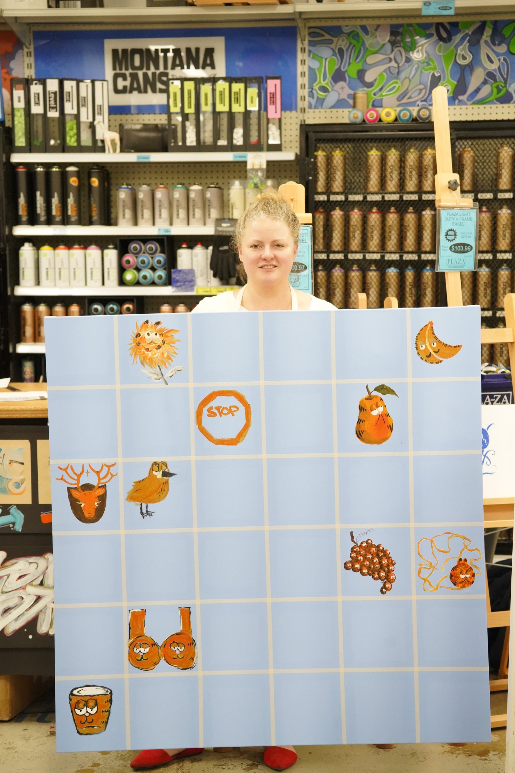 Kate Parnell holding up a painting mosaic of many different artists painting garfield from memory at Plaza Art in Washington, DC. Jan. 31, 2020.